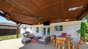 An outdoor patio with a covered seating area, a grill, and a TV mounted on the wall. - Bexar Charming 3-bedroom MidTerm (Arlington)