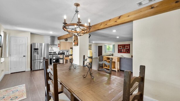 A spacious dining area with a wooden table and chairs, a chandelier, and a kitchen in the background. - Bexar Charming 3-bedroom MidTerm (Arlington)