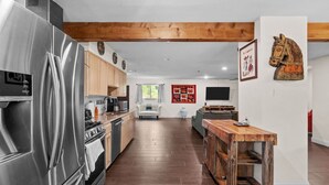 A modern kitchen with stainless steel appliances, wooden cabinets, and a wooden bar counter. - Bexar Charming 3-bedroom MidTerm (Arlington)