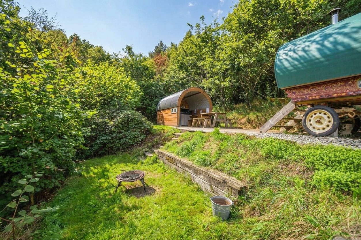 A rustic wooden house with an attached green water tank, surrounded by lush greenery.