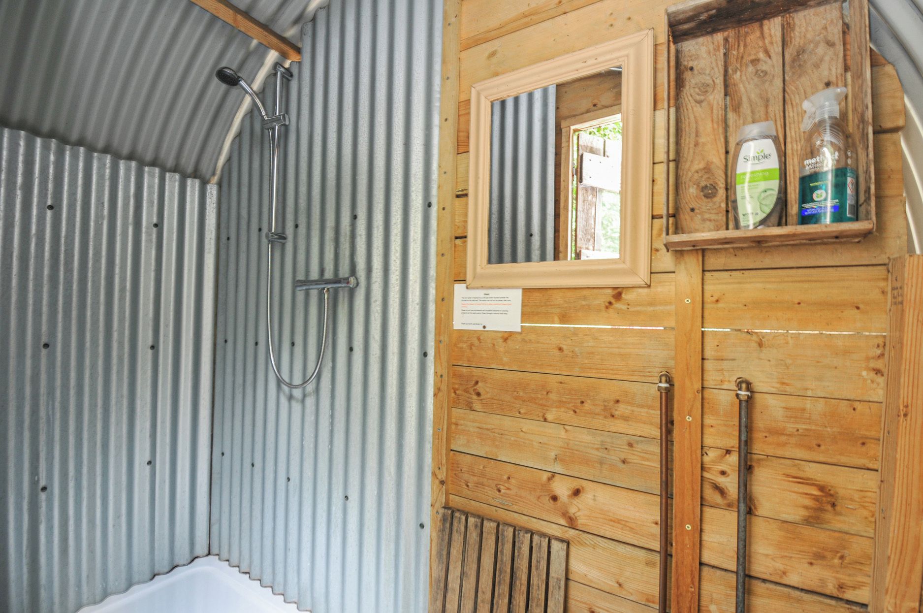 A bathroom with a shower, wooden cabinets, and a window.