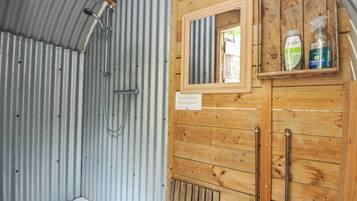 A bathroom with a shower, wooden cabinets, and a window.