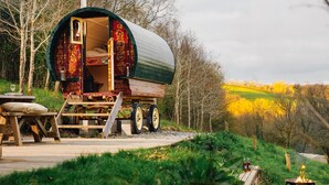 Une caravane immobile, dotée d’une entrée ouverte, d’une terrasse en bois et d’un foyer.
