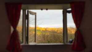 Une pièce dotée d’une fenêtre donnant sur un paysage arboré et un ciel dégagé.