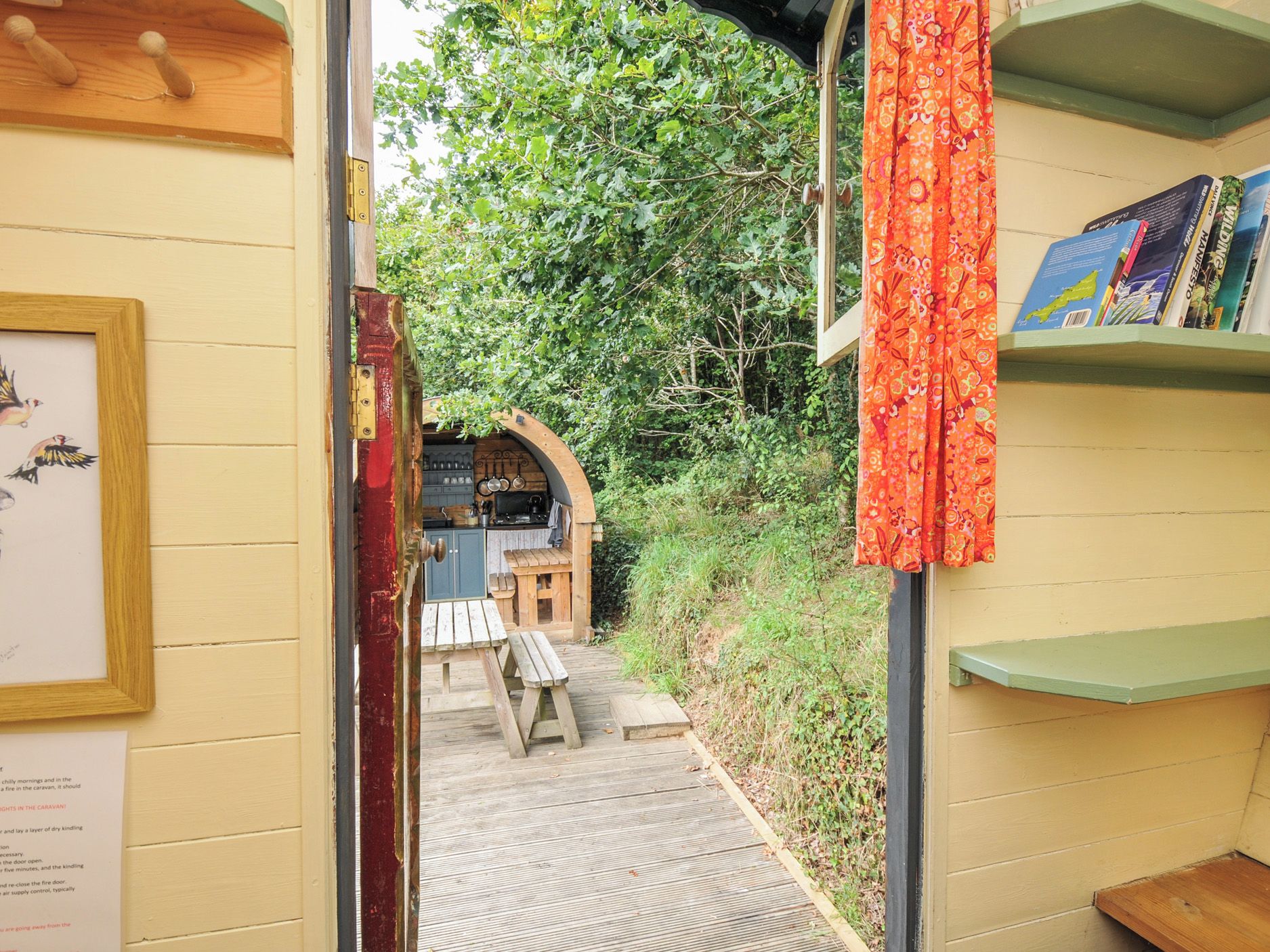 A narrow wooden pathway leading to a rustic outdoor seating area with a table and chairs.