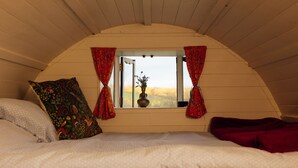 Une chambre confortable avec un lit, une fenêtre avec des rideaux et une vue sur l’extérieur.