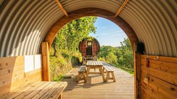 A wooden deck leading to a rustic cabin with a metal archway.