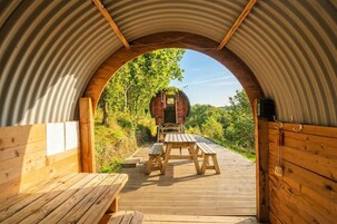 Una terraza de madera que conduce a una cabaña rústica con un arco de metal.
