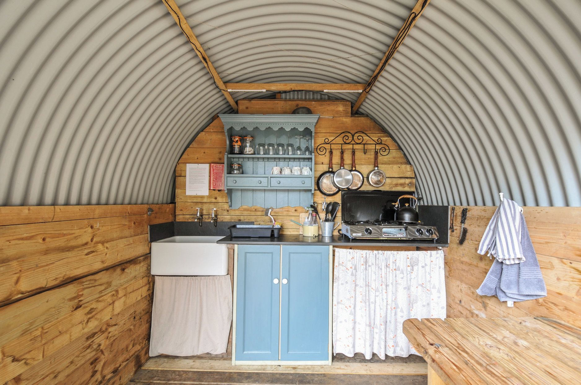 A compact kitchen with a sink, stove, and wooden cabinets.