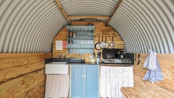 A compact kitchen with a sink, stove, and wooden cabinets.