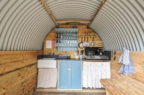 A compact kitchen with a sink, stove, and wooden cabinets. - Goldfinch (Launceston)