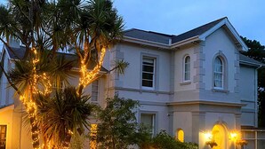 A large, two-story building with a symmetrical facade, large windows, and a central entrance with a doorway. - Muntham Luxury Town House With Hot Tub (Torquay)