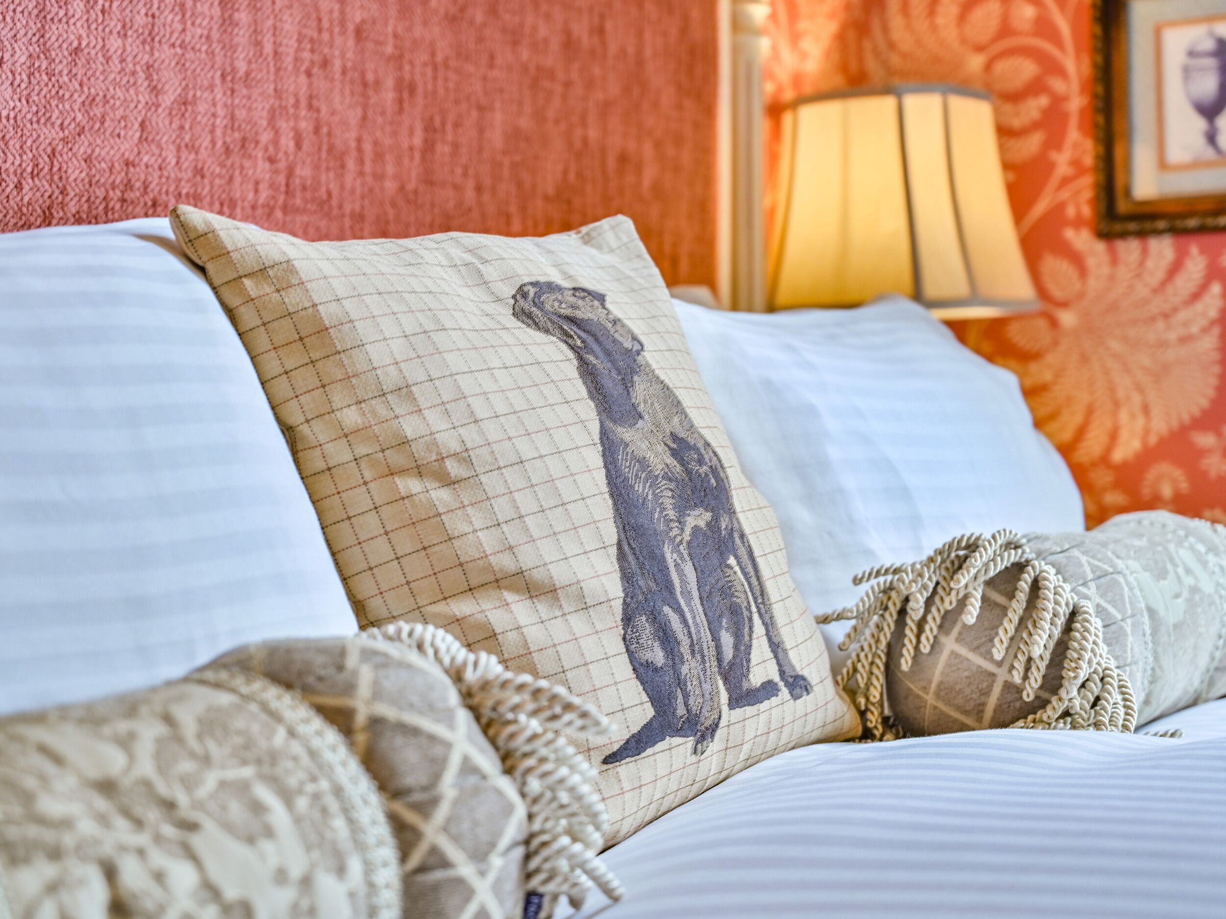 A bed with patterned pillows, a lamp, and a framed picture on the wall.