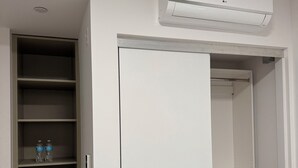 Ett rum med en vit garderob, en stängd dörr och en luftkonditioneringsanläggning som är monterad på väggen.