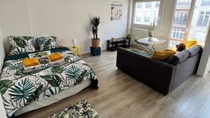 Ein modernes Wohnzimmer mit Bett, Sofa und einem kleinen Tisch mit Pflanze.