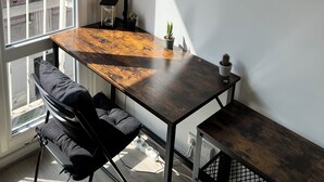 Eine moderne Wohnung mit Holztisch, schwarzem Stuhl und einer großen Wanduhr.