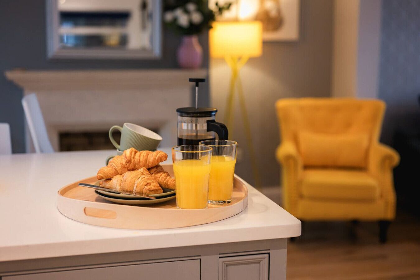 A breakfast tray with croissants and orange juice on a kitchen counter.