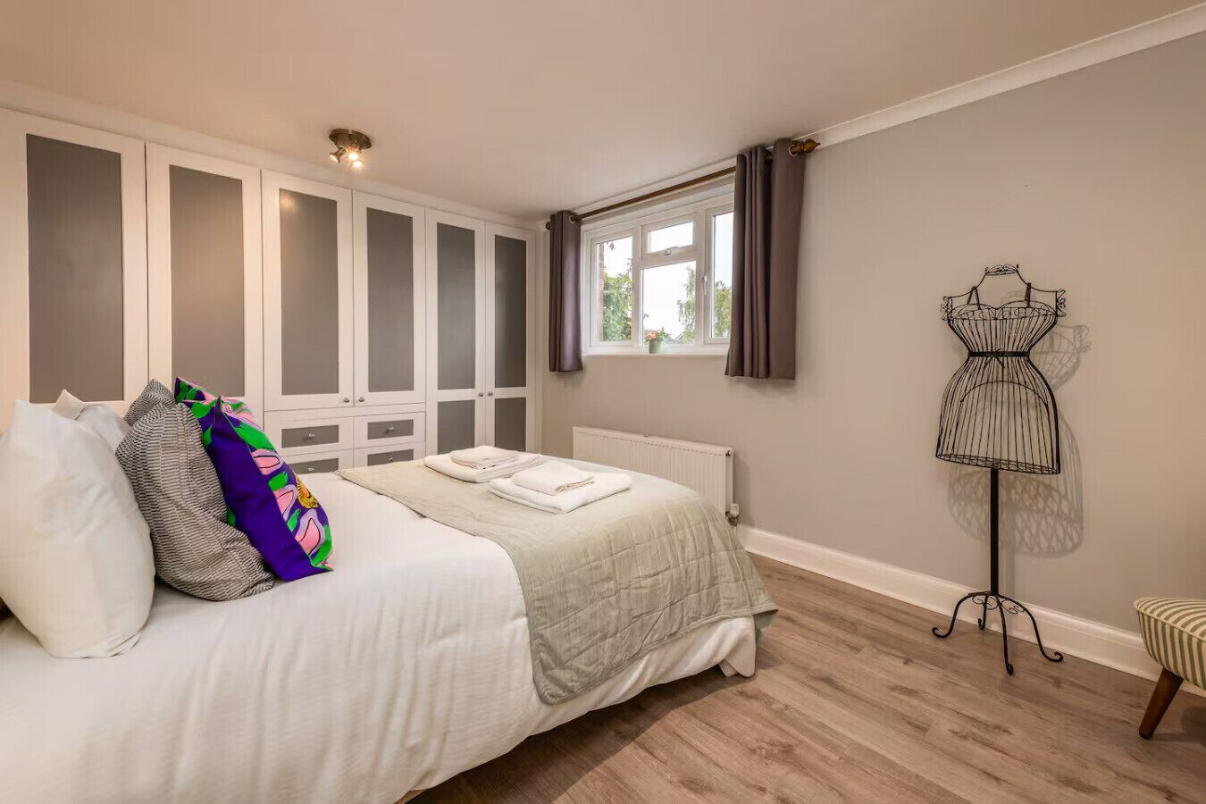 Une chambre à coucher comprenant un lit, une armoire, un radiateur, une fenêtre avec des rideaux et un mannequin.