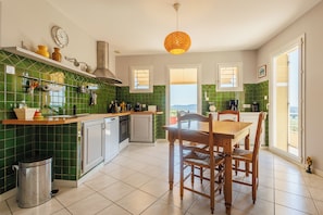 Een keuken met groene tegels, een houten eettafel en stoelen.