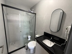A modern bathroom with a glass-enclosed shower, a white toilet, a black sink, and a mirror. - Solaz - Miramar Hospedagens  (João Pessoa)