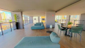 Ein geräumiger Balkon mit einer Couch, Esstisch, Stühlen und Topfpflanzen.