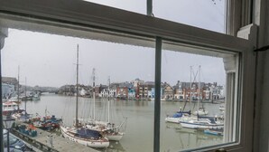 A view of a harbor with boats docked, buildings in the background, and a clear sky. - Harbourside (Weymouth)