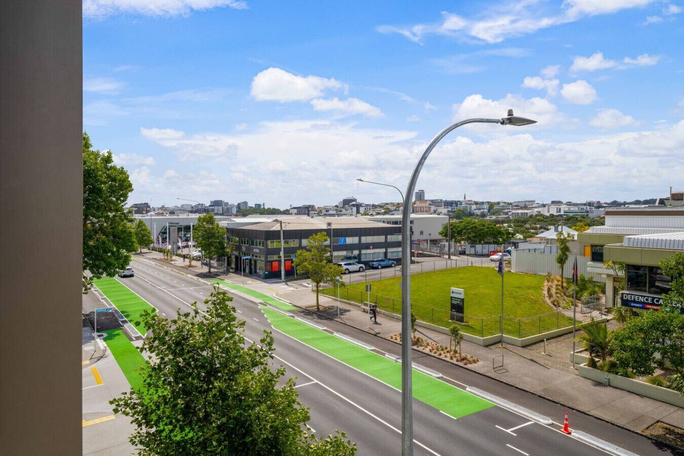 Vista d'un carrer urbà amb un carril bici verd, edificis moderns i un cel serè.
