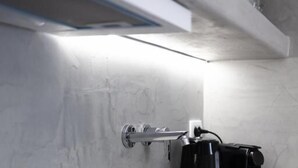 Eine Küche mit Herd, Wasserkocher und Kaffeemaschine auf einer Arbeitsfläche.