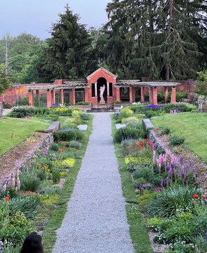 A garden pathway leading to a brick building with a statue in the center.