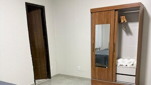 A room with two beds, a wooden wardrobe, and a door. - Arbo Belém Quartos padrão Anfitrião 360 (Belém)