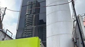 A modern building with a reflective glass facade, a large cylindrical structure, and a blue shuttered entrance. - Arbo Belém Quartos padrão Anfitrião 360 (Belém)