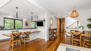 Eine moderne Küche mit einer großen Kochinsel, Holzstühlen und einem Essbereich mit Holztisch und -stühlen.