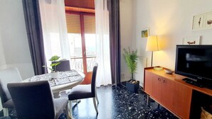 Ett hotellrum med ett matbord, stolar, en TV, en lampa och en krukväxt.