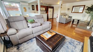 A living room with a grey sofa, a brown leather ottoman, and a blue and white patterned rug. - 1 Bed 1 bath Lakefront Apartment in Lake Hopatcong, NJ w/ lake access and kayaks (Jefferson)
