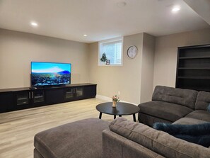 A living room with a flat-screen TV, a sofa, a coffee table, and a small decorative plant. - Willow Stay-Private 2-Bedroom Suite (Surrey)