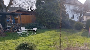 A well-maintained garden with a small tree, a wooden bench, and a table. - Vacation/ mechanic apartment Nikki (Argenthal)