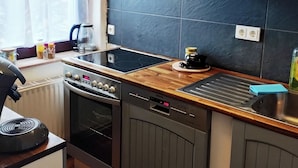 A compact kitchen with a stove, oven, dishwasher, and a small sink. - Vacation/ mechanic apartment Nikki (Argenthal)