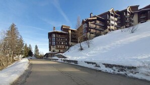 Una carretera cubierta de nieve con un conjunto de edificios al fondo.