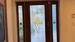 A foyer with a wooden door, a patterned rug, and a decorative mermaid sculpture. - Spacious 4-bedroom house on beautiful Lake Apopka. (Apopka)