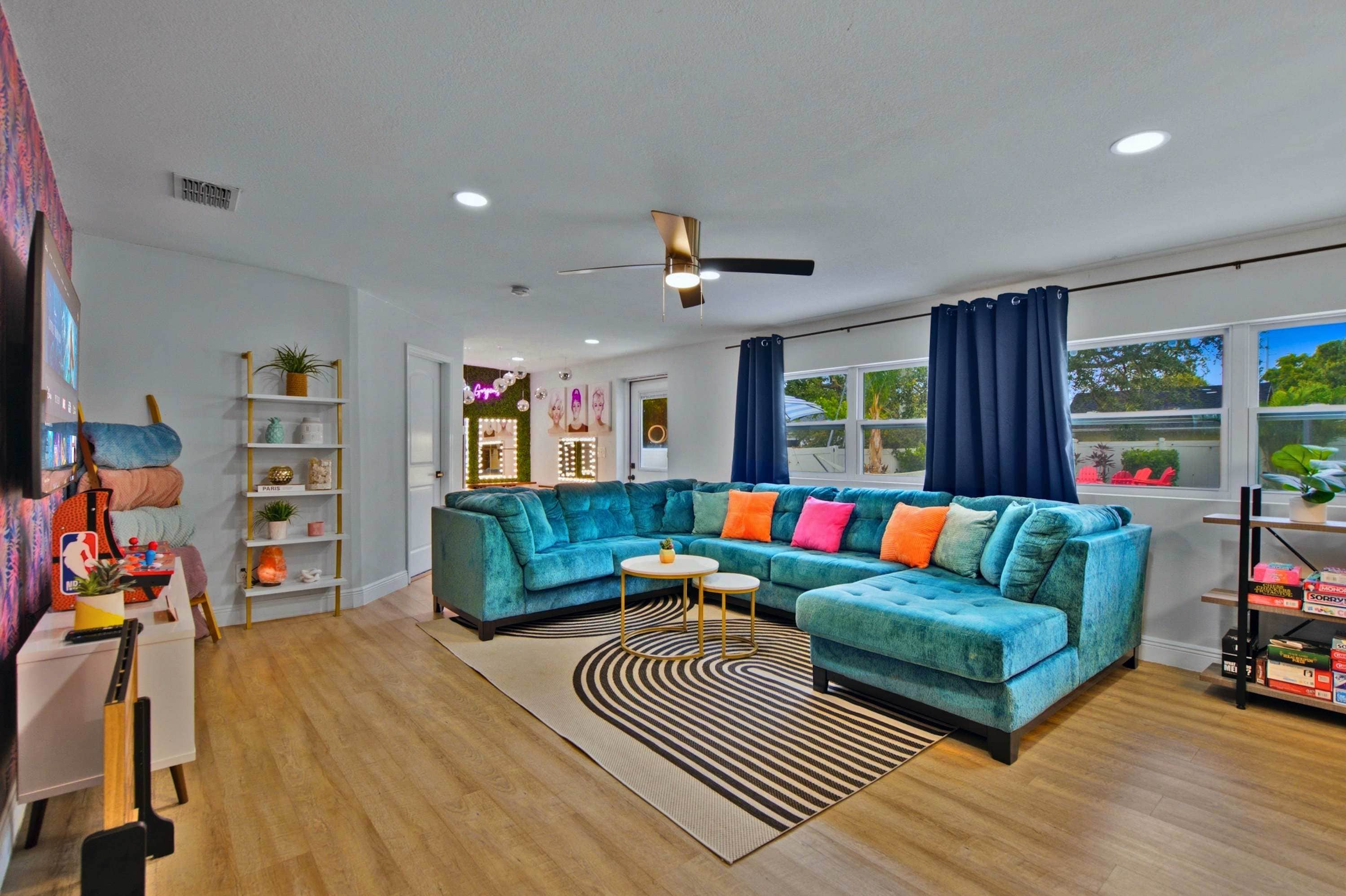 A modern living room with a sectional sofa, a flat-screen TV, and a ceiling fan.