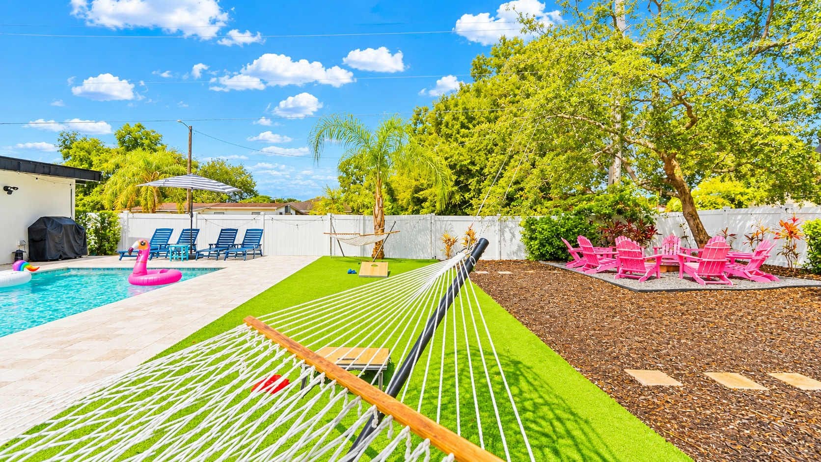 Ein Garten mit Schwimmbad, Hängematte und Sitzgelegenheit im Freien.