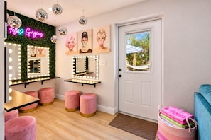 A room with a vanity mirror, lights, and a neon sign.