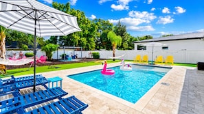 A swimming pool with lounge chairs and inflatable toys. - Tampa Backyard Oasis | Pool • Golf • Glam Room (Tampa)