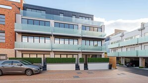 Een meerlaags gebouw met een modern architectuurontwerp, met een glazen gevel, een auto voor en een heldere lucht.