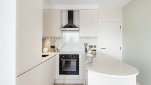 Eine moderne Küche mit weißen Schränken, einem eingebauten Backofen und einer Marmorarbeitsplatte.
