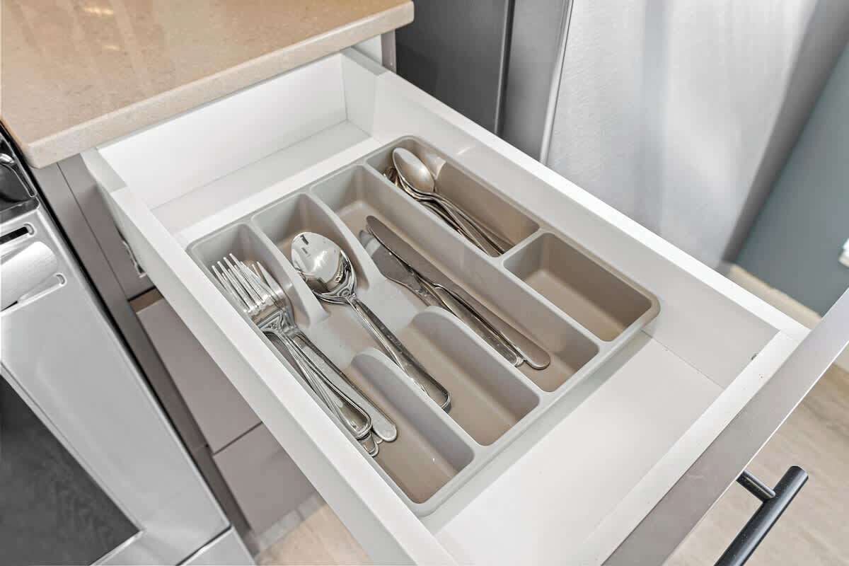 A kitchen drawer with utensils organized in compartments.