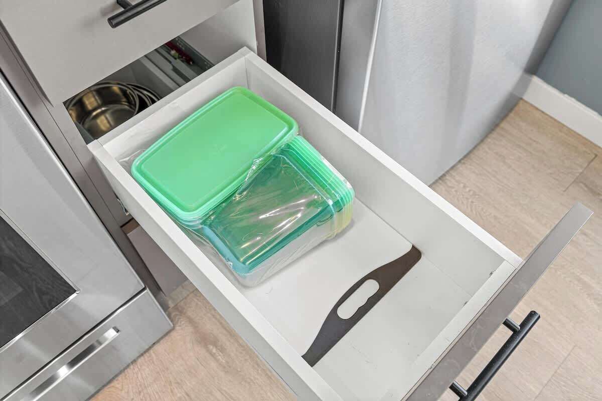 Eine Küchenschublade mit grünen Aufbewahrungsbehältern und einem schwarzen Küchenhelfer.