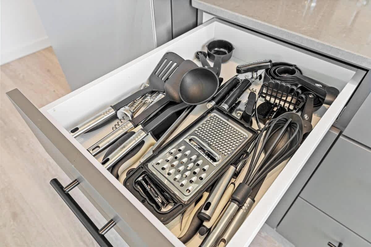 Un tiroir rempli d’ustensiles de cuisine, notamment des spatules, une râpe et un fouet.