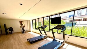 Academia com esteiras, bicicleta ergométrica e tela de televisão.