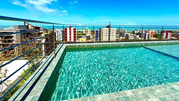 Piscina no terraço com vista para a cidade, rodeada por edifícios.